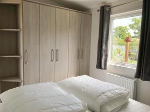 a bedroom with a white bed and a window at Chalet 579 op Recreatiepark De Wielen in Sint Maarten +21 photos
