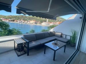 a couch on a balcony with a view of the water at Tisno Central Apartments in Tisno