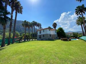 a house on a lawn with palm trees at Villa Merry - Dalyan Stonehouse with Palmtrees, 50m to River in Ortaca