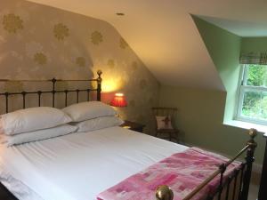 a bedroom with a large bed with white sheets and a window at Cauldholm in Moffat
