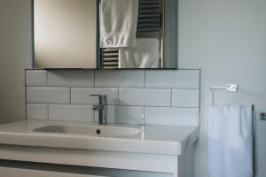 a white bathroom with a sink and a mirror at Lamb Cottage in Ballycastle +6 photos