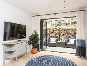 a living room with a tv and a sliding glass door at 3 Ty Stabal in Pwllheli