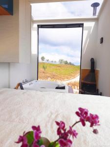 a bedroom with a bed with a view of a field at Refúgio Eco Boutique Tuiuva in Cristina
