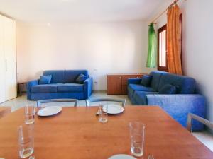 ein Wohnzimmer mit einem Tisch und blauen Sofas in der Unterkunft Residence Olimpo Poseidone in Santa Teresa Gallura