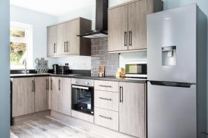 a kitchen with white appliances and wooden cabinets at Fully refurbished North Belfast Home 3 in Belfast
