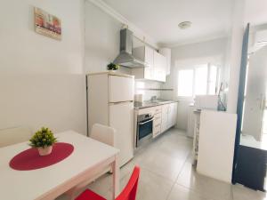 cocina blanca con mesa y nevera blanca en CENTER & WHITE TOWN Apartament, en Torremolinos