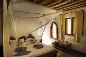 una camera da letto con un letto a baldacchino di Ujamaa Beach Resort a Makunduchi Altre 68 foto