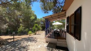 a house with a balcony with an umbrella at Mario & Nina - Portopino House in Porto Pino