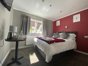 a red bedroom with a bed and a table at The Beeches, Ashby-de-la-Zouch in Ashby de la Zouch