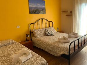 Colle Veralli في Foce: غرفة نوم بسريرين وجدار اصفر