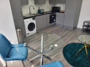 a kitchen with a glass table and a washing machine at 1 Bed Flat, Fibre Broadband, New, Washer Dryer, 10 mins from city centre in Dartford