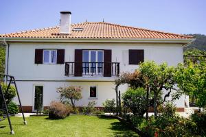 a white house with a balcony and a yard at Casa do Avô Horácio in Viana do Castelo
