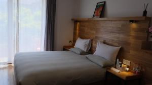 a bedroom with a large white bed and a window at Rock&Wood Cozy House in Hangzhou