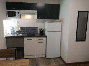 a kitchen with a white refrigerator and a sink at 2 appartements au choix centre ville de Souillac entre Sarlat et Rocamadour in Souillac