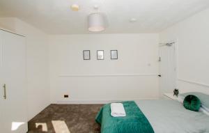 a bedroom with white walls and a bed with a green blanket at Ultimate Comfort 4-Bedroom Property for 7 People in Bromley