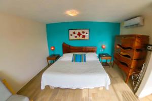 1 dormitorio con cama blanca y pared azul en Villa Los Corales, en Sayulita
