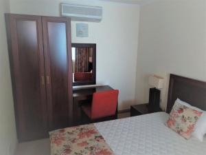 a bedroom with a bed and a desk and a red chair at Апартамент Сънсет Ризорт in Pomorie