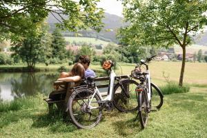 two people sitting on a bench next to bikes at Am Rain - Natur und Spa in Winden im Elztal