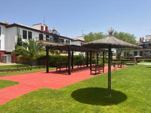 a park with benches and an umbrella and grass at Ayamonte - Vista Esuri Golf and Beach in Huelva