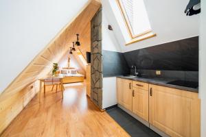 a kitchen with wooden cabinets and a staircase with a window at Pokoje Gościnne Pod Łosiówkami in Poronin
