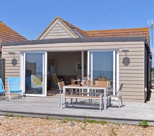a patio with a table and chairs on a deck at Pevensey Beach Retreat in Pevensey