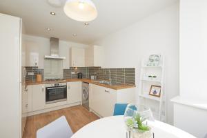 a kitchen with white cabinets and a white table at Royal Derby Hospital 3 bed Town House in Derby