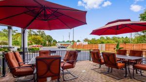 a patio with tables and chairs and red umbrellas at Best Western Plus Newport News in Newport News