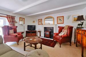 a living room with red chairs and a fireplace at Finest Retreats - River Cottage in Nancledra
