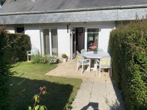 une table et des chaises devant une maison dans l'établissement Résidence Les jardins de Courseulles F3, à Courseulles-sur-Mer