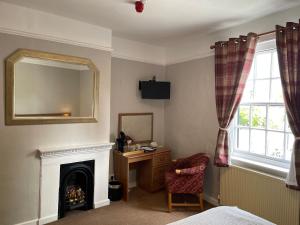 a bedroom with a fireplace and a mirror and a chair at The Swan Inn in East Ilsley