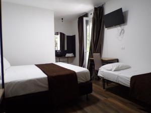 a hotel room with two beds and a desk and a window at Hotel Nord Est in Riccione