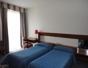 una camera d'albergo con due letti e una finestra di Cravero Rooms a Caltignaga