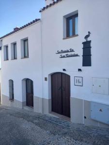 a white building with doors and a bird on the side at Hotel Rural La Posada de las Cigüeñas in Jerez de los Caballeros