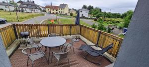 ein Balkon mit Tisch und Stühlen und einem Sonnenschirm in der Unterkunft Ferienhaus an See in Nohfelden