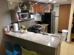 a kitchen with a counter top with a stove and a refrigerator at Navona Towers Amplio Apart, Dos Noches minimo, para 4 personas lo mejor de Panamá in Panama City