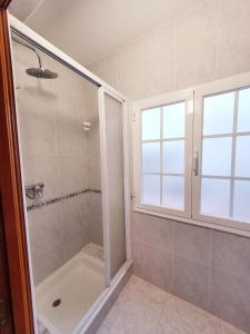uma casa de banho com um chuveiro e uma porta de vidro em Hostal Cachiño em San Mamede de Carnota
