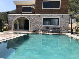 a swimming pool with blue water in front of a house at Silyan Villas in Antalya