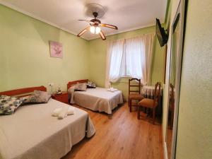 San Mamede de CarnotaにあるHostal Cachiñoのベッド2台と天井ファンが備わる客室です。