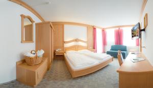 Pokój hotelowy z łóżkiem i niebieskim krzesłem w obiekcie Hotel zum grünen Tor w mieście Tux