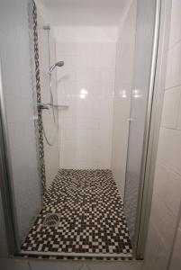 uma casa de banho com um chuveiro e piso em azulejo preto e branco em Haus Strandgang, Whg 2 em Kellenhusen