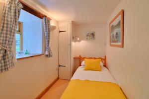 a small bedroom with a yellow bed and a window at Finest Retreats - The Barn in Nancledra