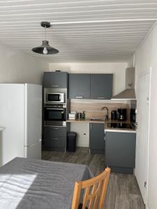 a kitchen with gray cabinets and a table with a chair at Charmante maison de ville avec parking à côté. in Morlaix