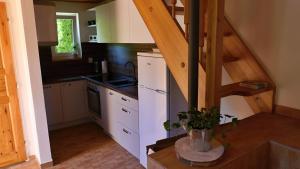 a kitchen with white cabinets and a wooden staircase at Chata u bazénu in Metylovice