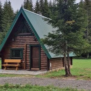 a log cabin with a bench next to a tree at Rajska suma in Žabljak