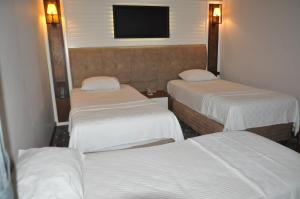 um quarto de hotel com três camas e uma televisão em Jolnar garden hotel em Macka