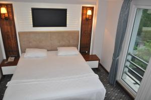 a bedroom with a bed with a flat screen tv at Jolnar garden hotel in Macka