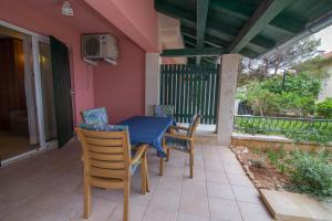 un patio con una mesa azul y sillas en un porche en Apartman Punta A2+2 en Veli Lošinj