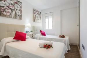 2 camas en una habitación con almohadas rojas. en Ático Avda Cádiz Playa, en Cádiz