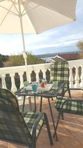 a table and chairs on a balcony with an umbrella at Apartman studio Dino Klimno in Klimno