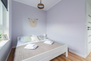 a white bedroom with a bed with towels on it at Flatbook Apartamenty - Sztutowo Dom Morska in Sztutowo